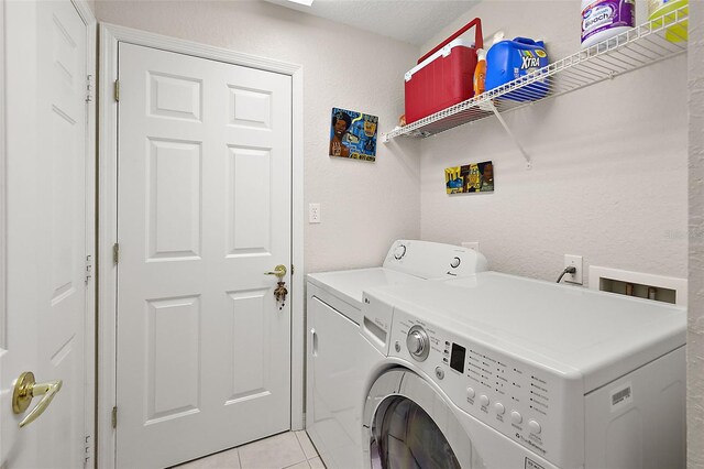 washroom with light tile patterned floors, a textured ceiling, and washer and dryer