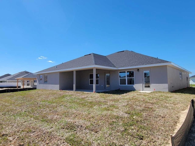 rear view of property with a lawn and stucco siding