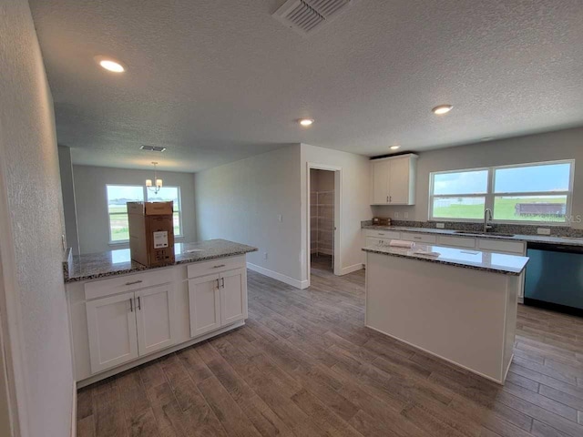 kitchen featuring visible vents, dishwasher, wood finished floors, white cabinetry, and a sink