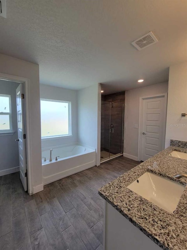 bathroom featuring wood finished floors, visible vents, a stall shower, a sink, and a bath