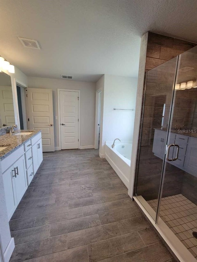 full bath featuring visible vents, a stall shower, wood finished floors, a bath, and vanity