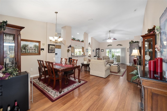 dining space with lofted ceiling, hardwood / wood-style floors, and ceiling fan with notable chandelier