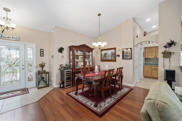 dining room featuring lofted ceiling, light hardwood / wood-style floors, a notable chandelier, and beverage cooler