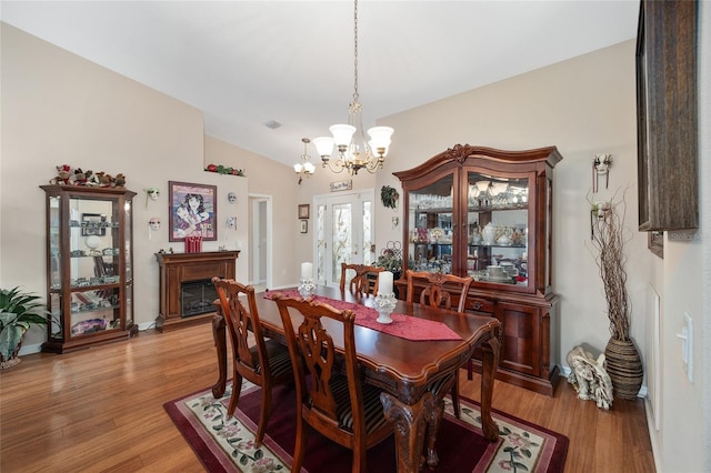 dining area featuring light hardwood / wood-style flooring, vaulted ceiling, and an inviting chandelier