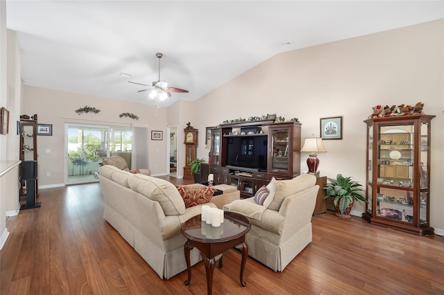 living room featuring dark wood-type flooring, ceiling fan, and vaulted ceiling