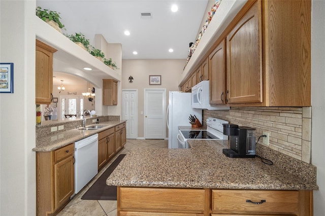 kitchen featuring white appliances, sink, kitchen peninsula, light tile patterned flooring, and tasteful backsplash