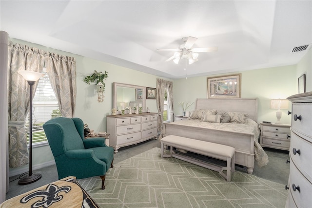 bedroom with a raised ceiling, ceiling fan, and carpet