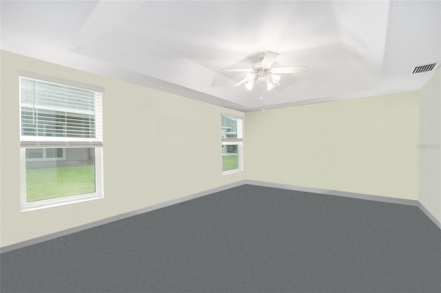 carpeted spare room with a raised ceiling and ceiling fan