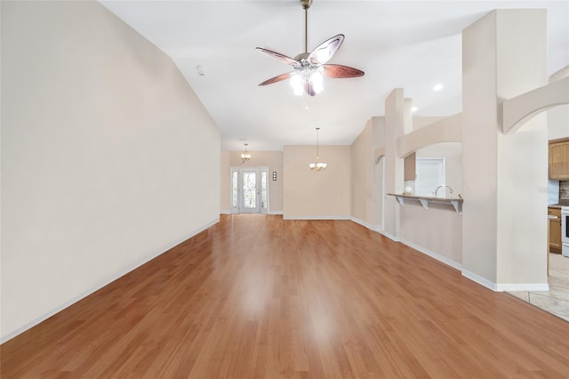 16369 SW 14th Avenue Rd, Ocala, FL 34473 - unfurnished living room with a ceiling fan, light wood-style floors, lofted ceiling, arched walkways, and a chandelier