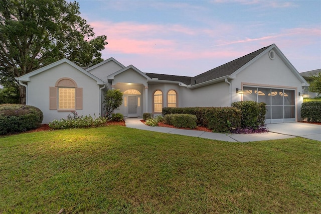 single story home with a front lawn, concrete driveway, stucco siding, and an attached garage