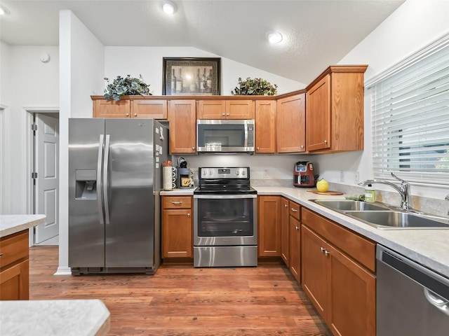 kitchen featuring appliances with stainless steel finishes, hardwood / wood-style floors, sink, and lofted ceiling