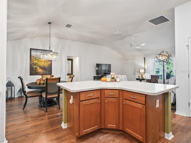 kitchen featuring ceiling fan with notable chandelier, dark hardwood / wood-style floors, a center island, and pendant lighting