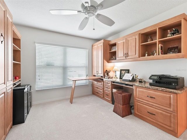 office with built in desk, ceiling fan, and light colored carpet