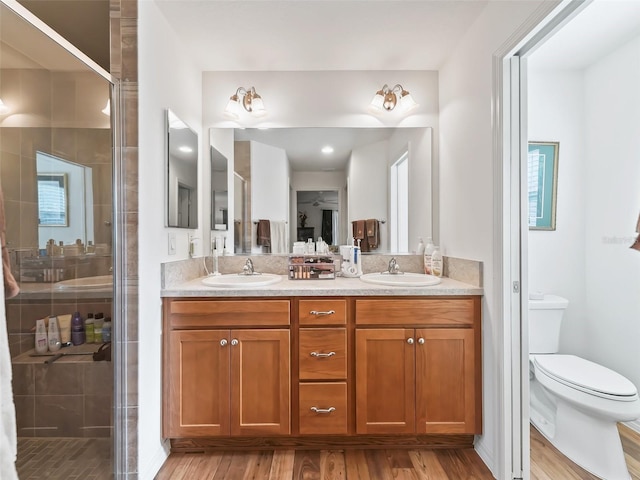 bathroom with wood-type flooring, vanity, toilet, and an enclosed shower