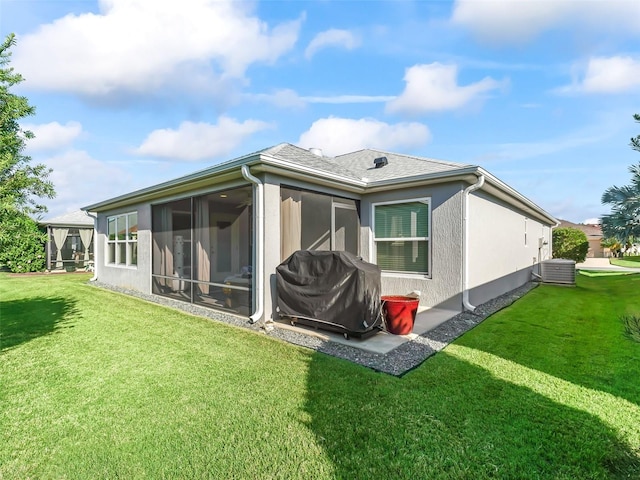 rear view of property featuring central AC unit, a sunroom, and a lawn