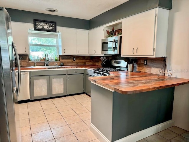 kitchen with white cabinets, light tile patterned flooring, sink, stainless steel appliances, and decorative backsplash