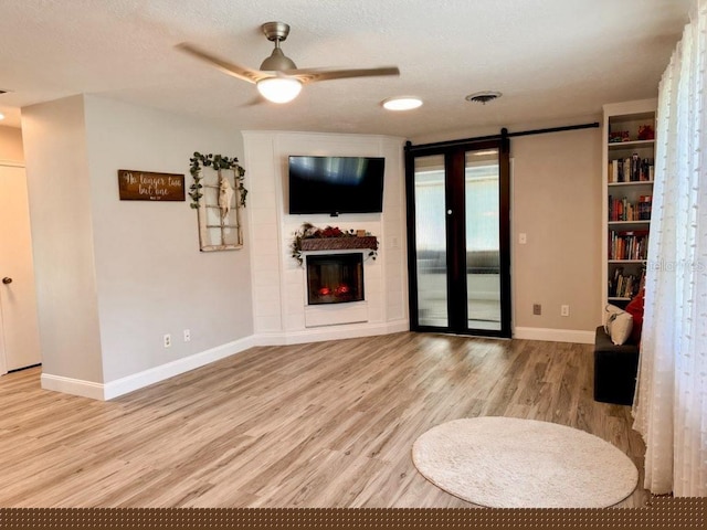 unfurnished living room featuring light wood-type flooring, ceiling fan, and a textured ceiling