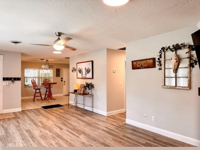 interior space with light hardwood / wood-style floors, ceiling fan, and a textured ceiling