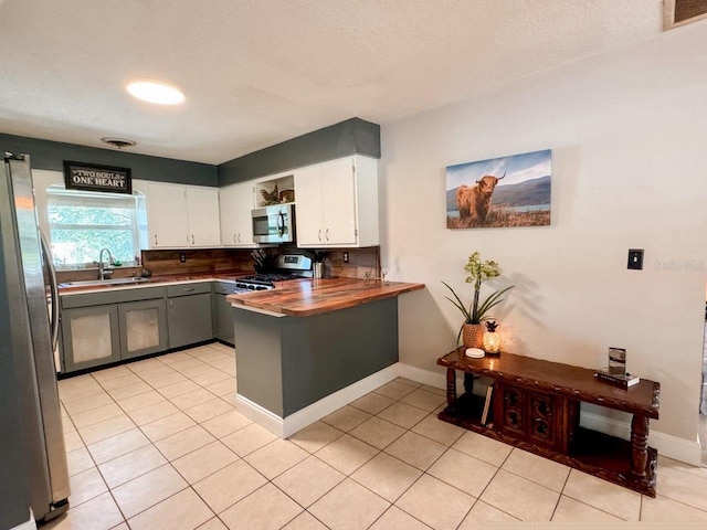 kitchen with light tile patterned flooring, stainless steel appliances, sink, and white cabinetry