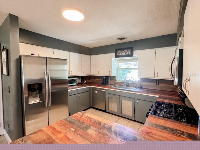 kitchen with stainless steel appliances, sink, and white cabinetry