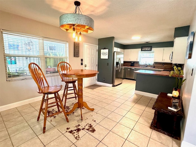 dining space featuring a textured ceiling, light tile patterned floors, and sink