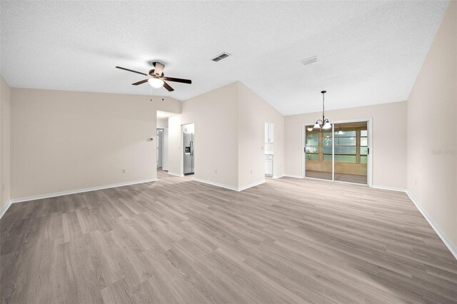 unfurnished living room with light wood-type flooring, ceiling fan with notable chandelier, lofted ceiling, and a textured ceiling