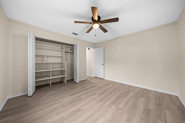 unfurnished bedroom featuring a closet, ceiling fan, light hardwood / wood-style floors, and a textured ceiling