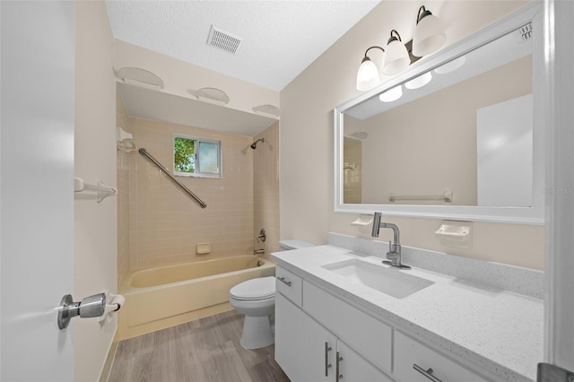 full bathroom with toilet, vanity, a textured ceiling, tiled shower / bath combo, and hardwood / wood-style flooring