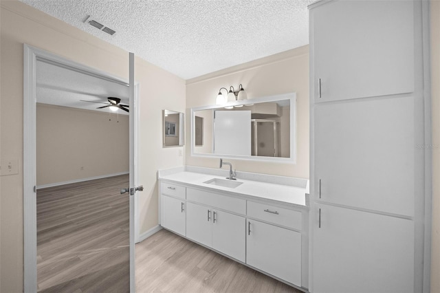 bathroom with a textured ceiling, vanity, ceiling fan, and hardwood / wood-style floors