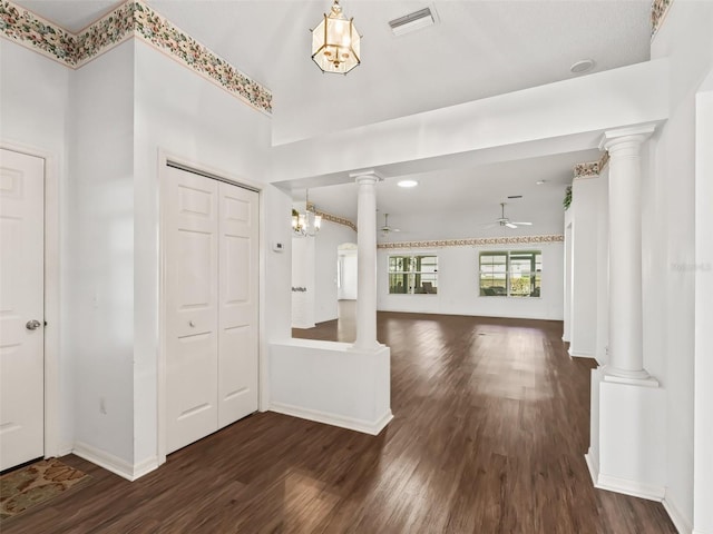 entryway featuring decorative columns, dark wood-type flooring, and ceiling fan with notable chandelier