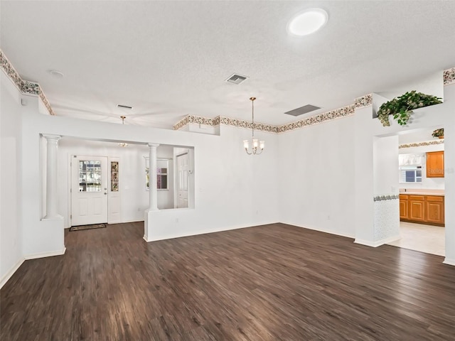 empty room with a textured ceiling, plenty of natural light, dark hardwood / wood-style floors, and a notable chandelier