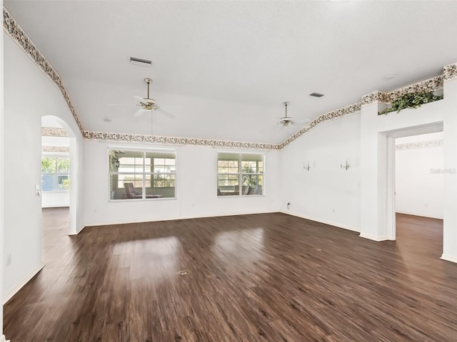 unfurnished living room with vaulted ceiling, a wealth of natural light, dark wood-type flooring, and ceiling fan