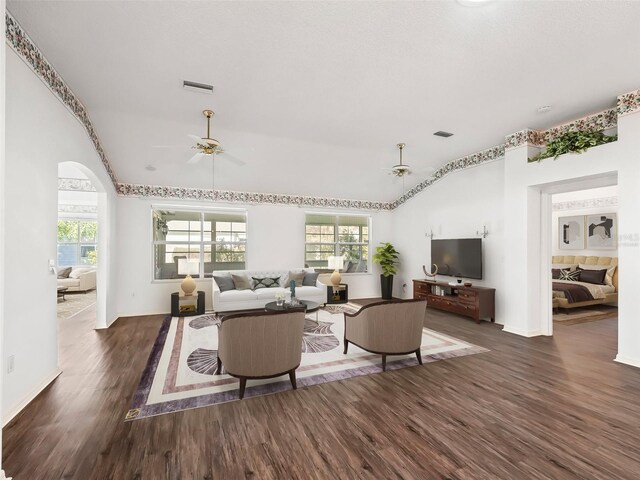 living room with ceiling fan, dark wood-type flooring, and vaulted ceiling