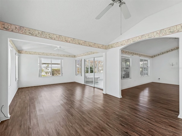 unfurnished living room with a textured ceiling, ceiling fan, dark wood-type flooring, and vaulted ceiling