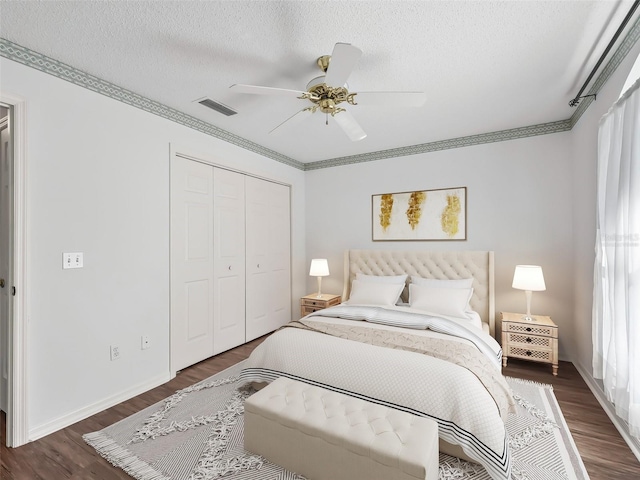 bedroom with dark wood-type flooring, ceiling fan, a textured ceiling, multiple windows, and a closet