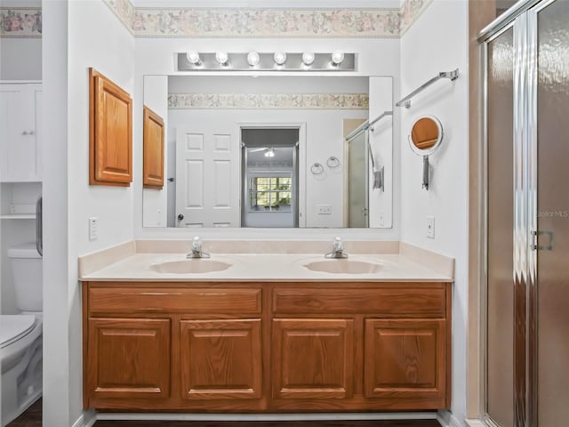 bathroom with vanity, toilet, and a shower with door