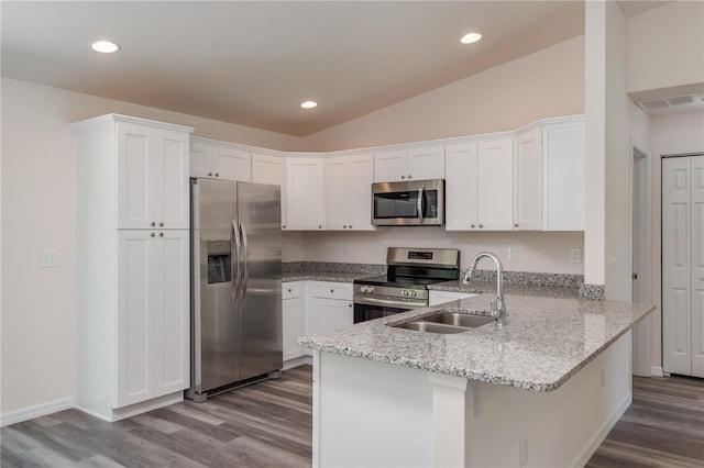 kitchen with kitchen peninsula, appliances with stainless steel finishes, light stone counters, sink, and white cabinets