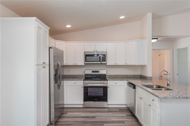 kitchen featuring kitchen peninsula, appliances with stainless steel finishes, sink, white cabinetry, and lofted ceiling