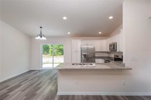 kitchen with kitchen peninsula, stainless steel appliances, sink, decorative light fixtures, and white cabinets