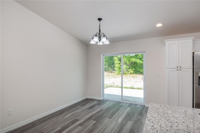 unfurnished dining area with dark hardwood / wood-style floors and an inviting chandelier