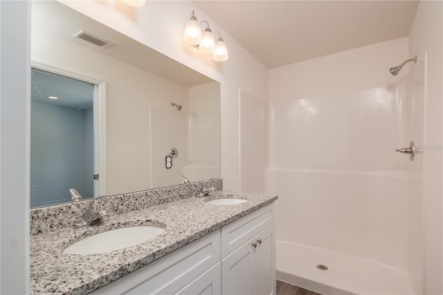 bathroom with a shower, vanity, and wood-type flooring