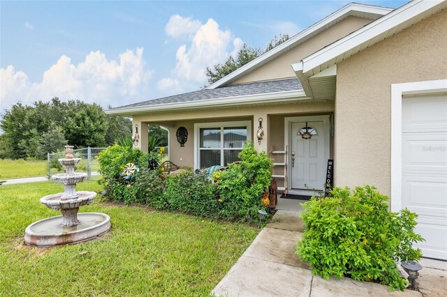 doorway to property with a garage and a yard