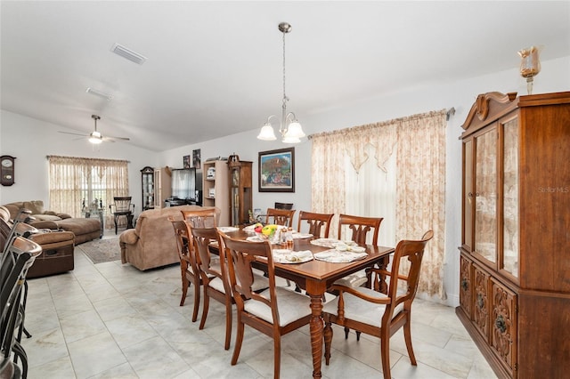 dining room featuring ceiling fan with notable chandelier and vaulted ceiling