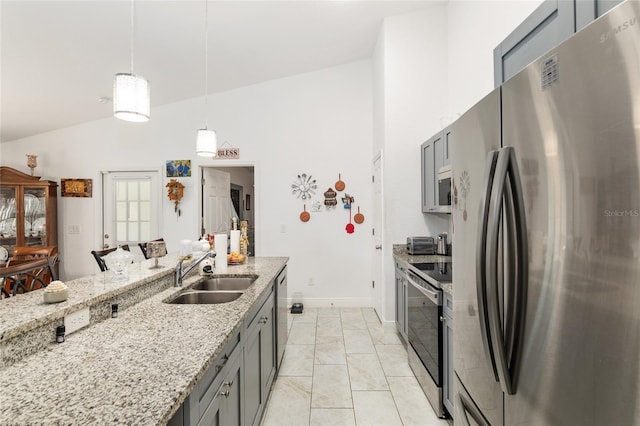 kitchen featuring appliances with stainless steel finishes, lofted ceiling, hanging light fixtures, light stone counters, and sink