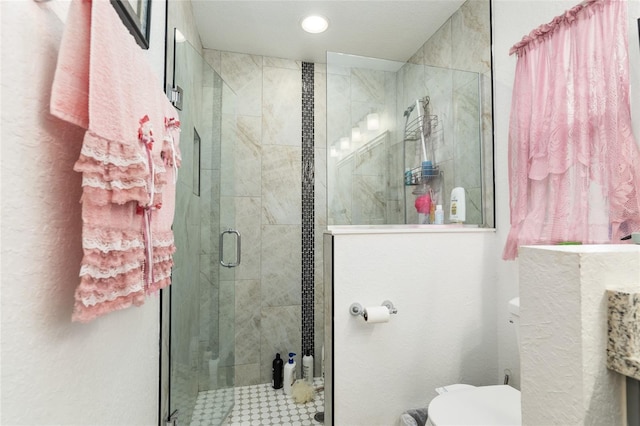 bathroom featuring toilet and a shower with shower door