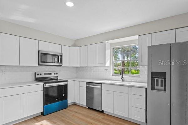 kitchen featuring white cabinets, appliances with stainless steel finishes, and light wood-type flooring