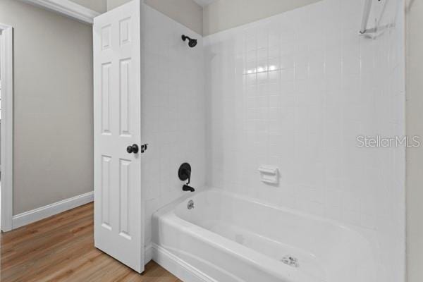 bathroom with hardwood / wood-style floors and tiled shower / bath