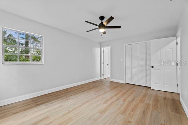 unfurnished bedroom with a closet, light hardwood / wood-style floors, and ceiling fan