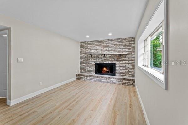 unfurnished living room featuring light wood-type flooring and a fireplace