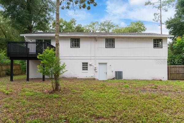 back of property featuring a lawn, a wooden deck, and cooling unit